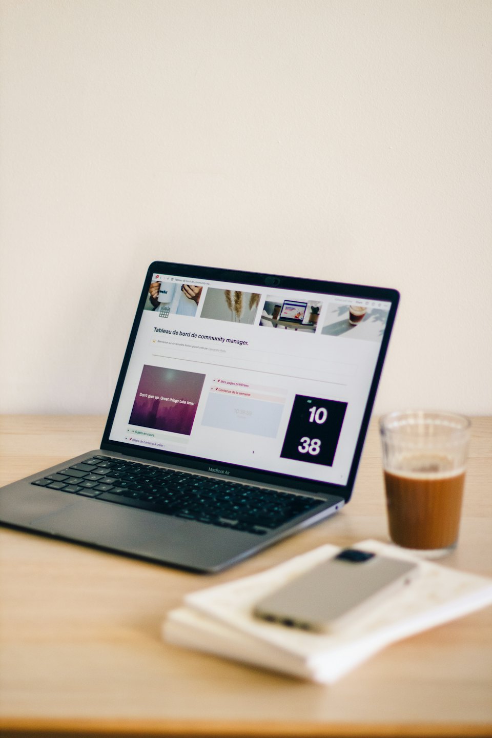 Laptop displaying dashboard on a wooden desk with iced coffee.